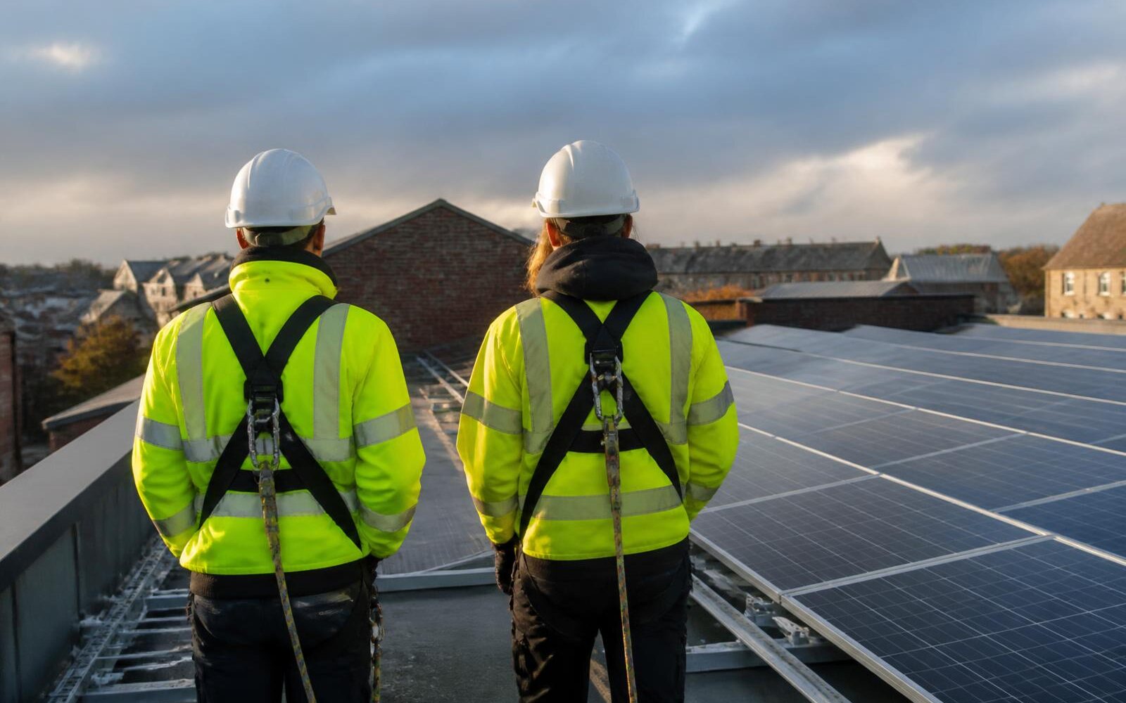 Engineers in hi-vis installing solar PV panels on a commercial warehouse roof